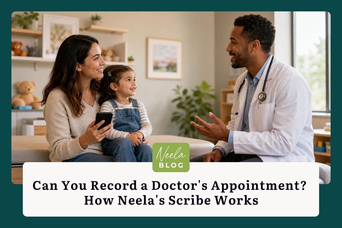 A parent holds their phone while listening attentively to a pediatrician during their young child's check-up in a bright, friendly doctor's office.