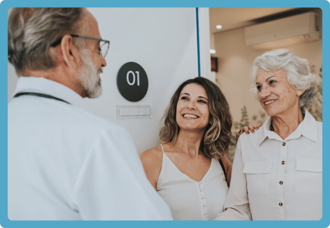 Caregiver and older adult talking with a doctor during a visit, illustrating how Neela helps prepare for and summarize appointments.