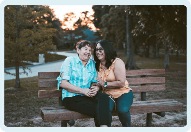Caregiver sitting with her older loved one outdoors, representing Neela’s support in staying organized and confident in caregiving.